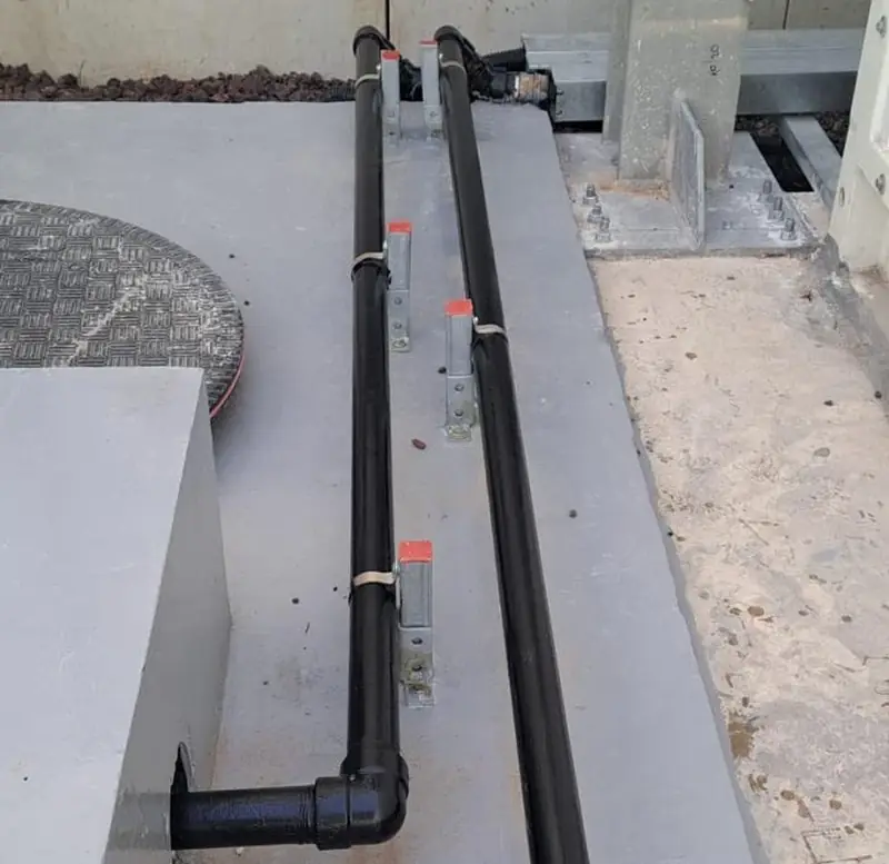 שני קווי צנרת דלק שחורים מעוגנים לבטון על אי משאבות