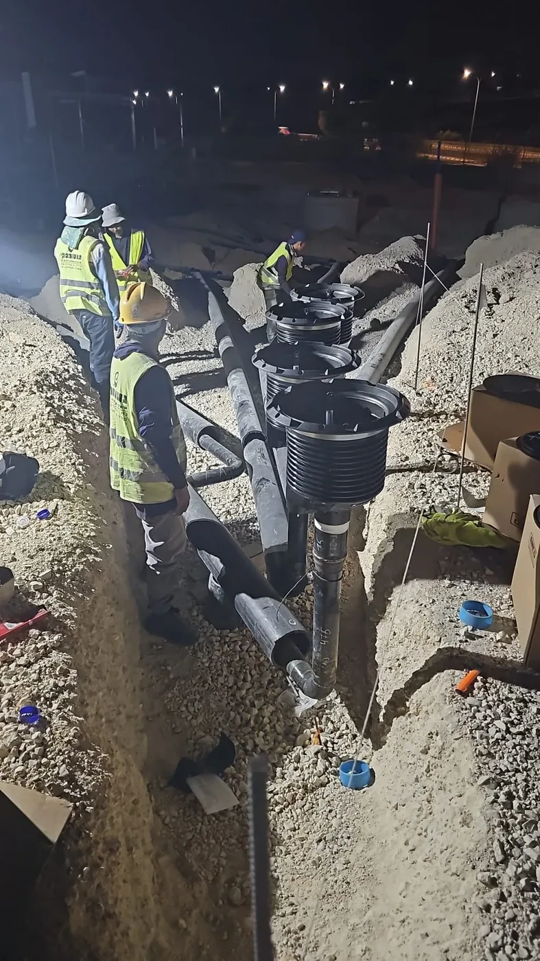 עובדים מתקינים שוחות וצנרת דלק בתעלה בעבודת לילה