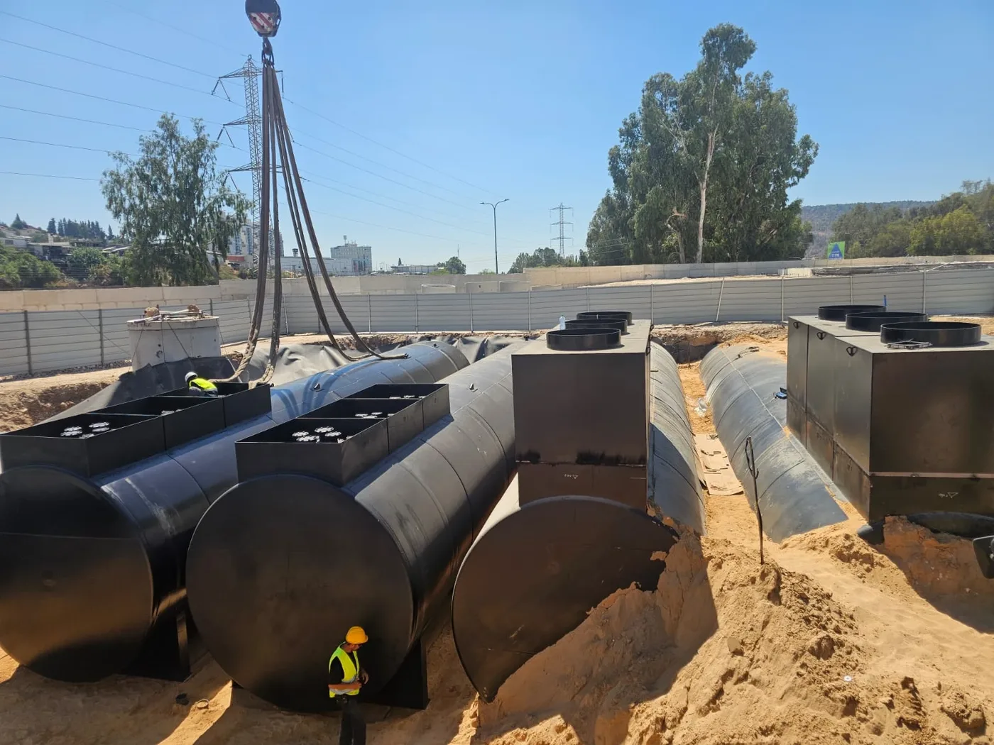 מיכלי דלק גליליים גדולים בבור מרופד ביריעת איטום, מנוף מעליהם